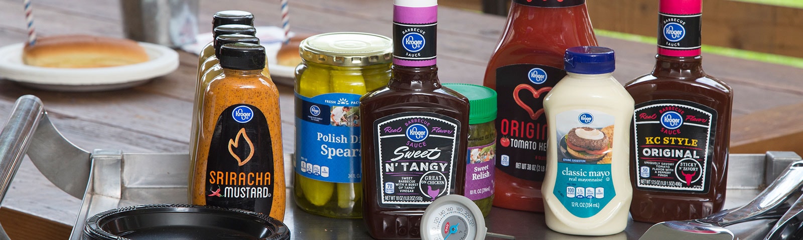 Various condiments sitting on a stainless steel table next to grilling utensils Various condiments sitting on a stainless steel table next to grilling utensils