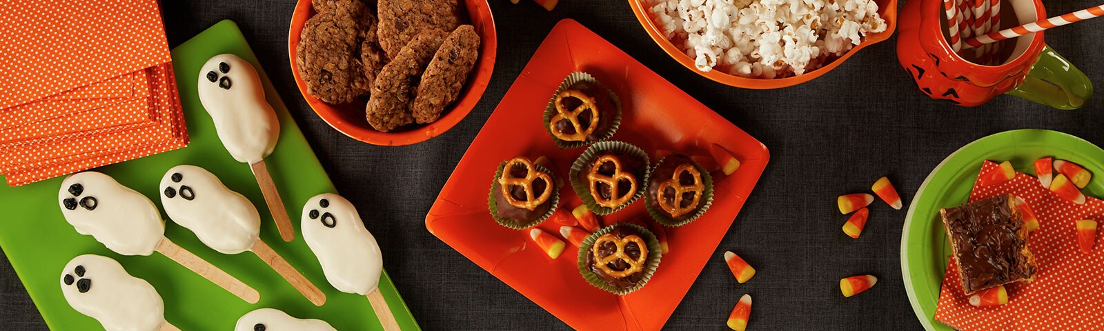 A table jam-packed with halloween treats and from cookies, to cake pops decorated as ghosts, to latex gloves filled with popcorn
