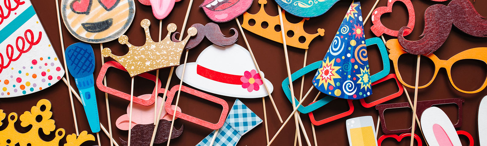 Photo booth props like cutout hats and sunglasses on wooden sticks