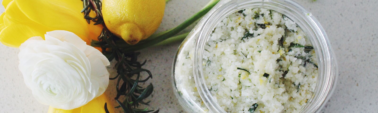 Salt scrub in mason jar next to white rose and rosemary Salt scrub in mason jar next to white rose and rosemary