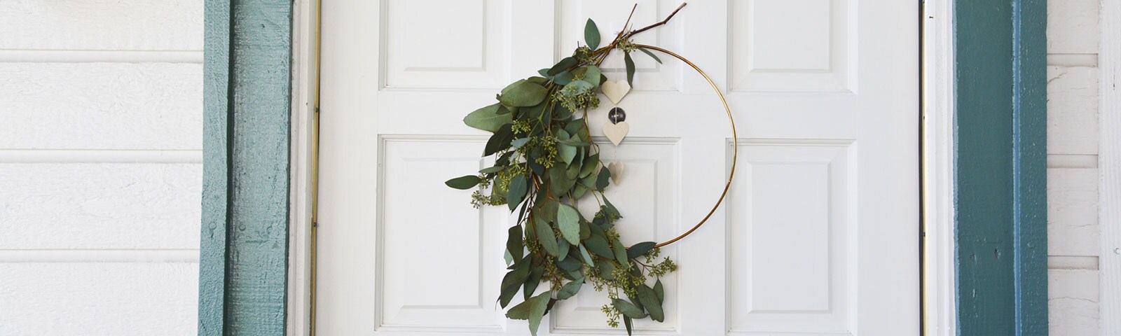 A white door with a handcrafted eucalyptus wreath hanging in the center