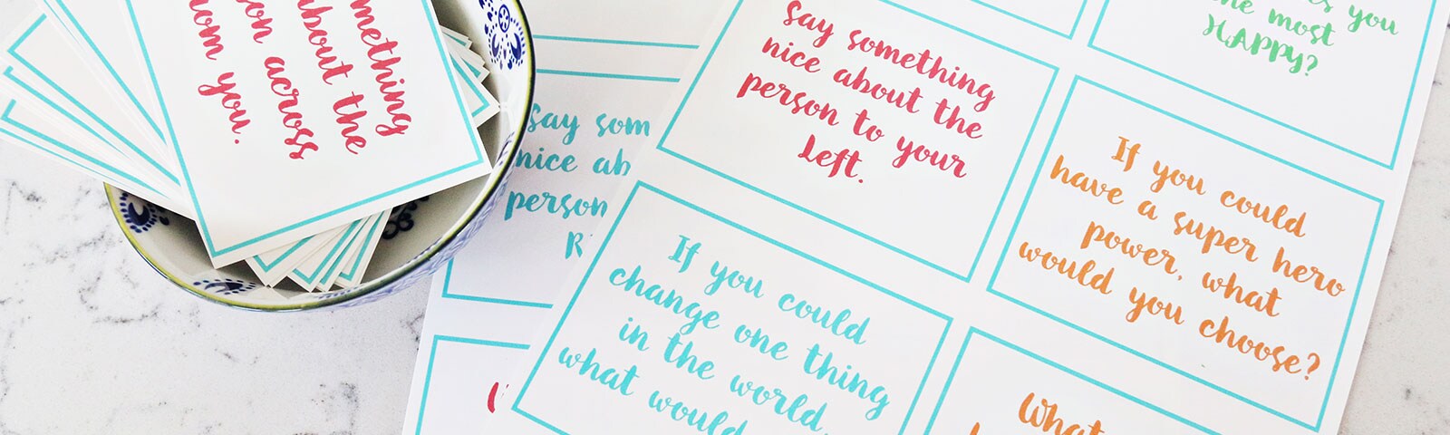 Note cards with conversation starters written in color in a bowl